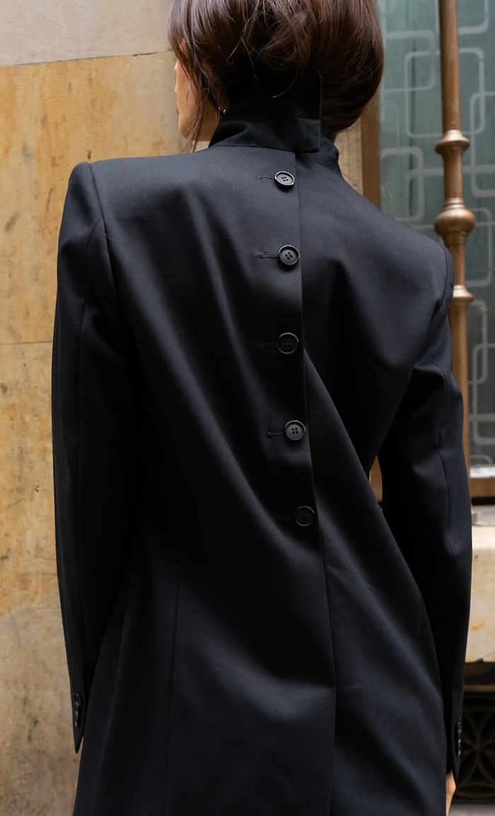 Model wearing a black blazer with buttons on the back