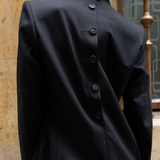 Model wearing a black blazer with buttons on the back