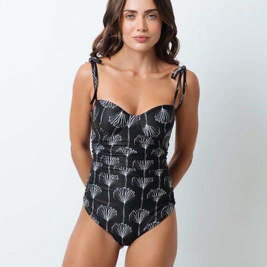 Woman wearing a black and white swimsuit. She's looking at the camera. The purpose of this image is to highlight the swimsuit by Mar de Lua.