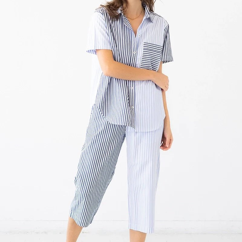 Image of a woman wearing a striped button down shirt and matching capri pants. She's standing against a white background. The purpose of this image is to highlight the clothing. 