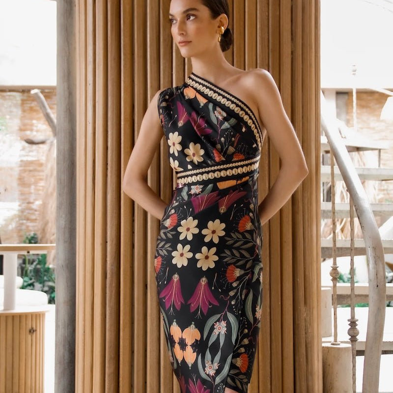 Image of a woman wearing a black sari dress with bright flowers. The purpose of this image is to highlight the dress, which is for sale at EVAMAIA boutique in Studio City, CA.