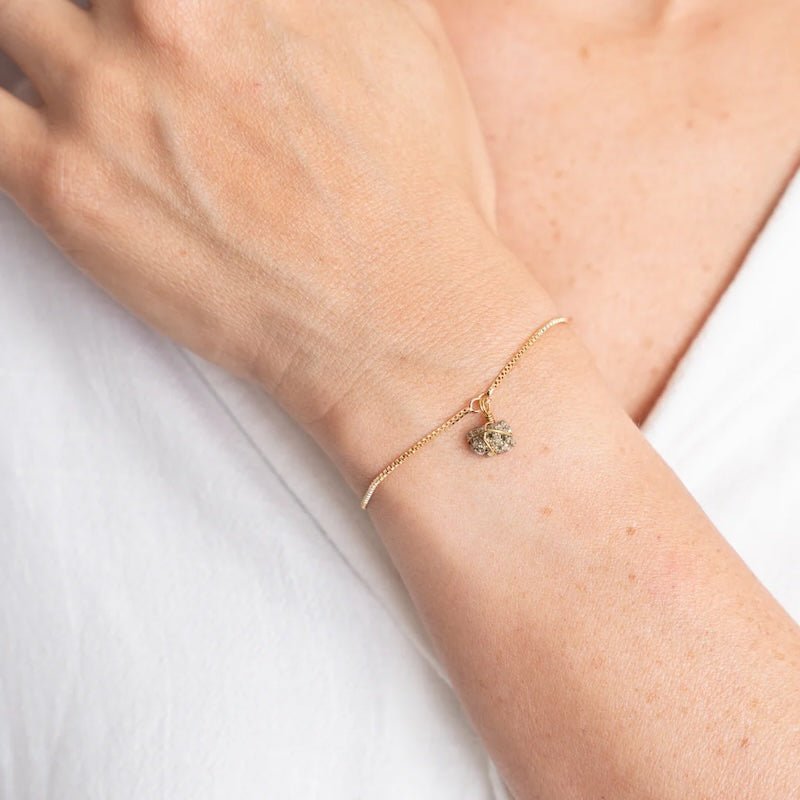 Close up image of a woman wearing a gold chain bracelet with an pyrite stone on it. The purpose of the image is to highlight the bracelet because it is on sale at EVAMAIA boutique in Studio City, CA.