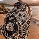 The designer of PLISSE, Paloma wearing the nazar kimono and wrap skirt. She is posing in the sand at a beach during golden hour. This is the back of this flowy kimono.