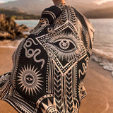 The designer of PLISSE, Paloma wearing the nazar kimono and wrap skirt. She is posing in the sand at a beach during golden hour. This is the back of this flowy kimono.