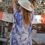 Image of the back of a woman. She's wearing a light blue kimono with the image of an eye on it. The purpose of this image is to highlight the kimono, which is for sale at EVAMAIA boutique in studio city, CA.