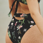 Close up image of the back of a woman. She's wearing a swimsuit with flowers. The purpose of this image is to highlight the swimsuit.