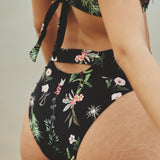 Close up image of the back of a woman. She's wearing a swimsuit with flowers. The purpose of this image is to highlight the swimsuit.