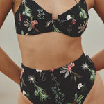 Close up image of a woman wearing a swimsuit. She's wearing a swimsuit with flowers. The purpose of this image is to highlight the swimsuit.