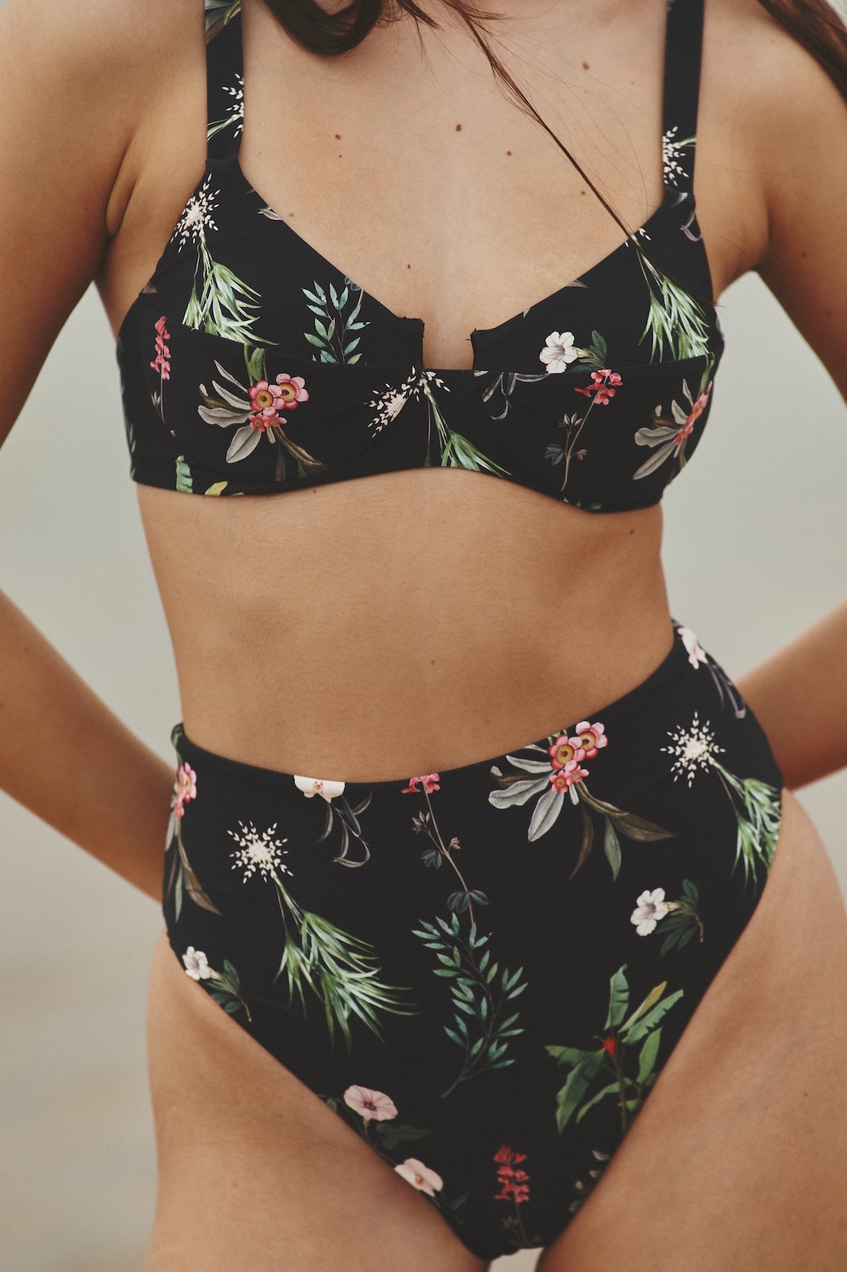 Close up image of a woman wearing a swimsuit. She's wearing a swimsuit with flowers. The purpose of this image is to highlight the swimsuit.