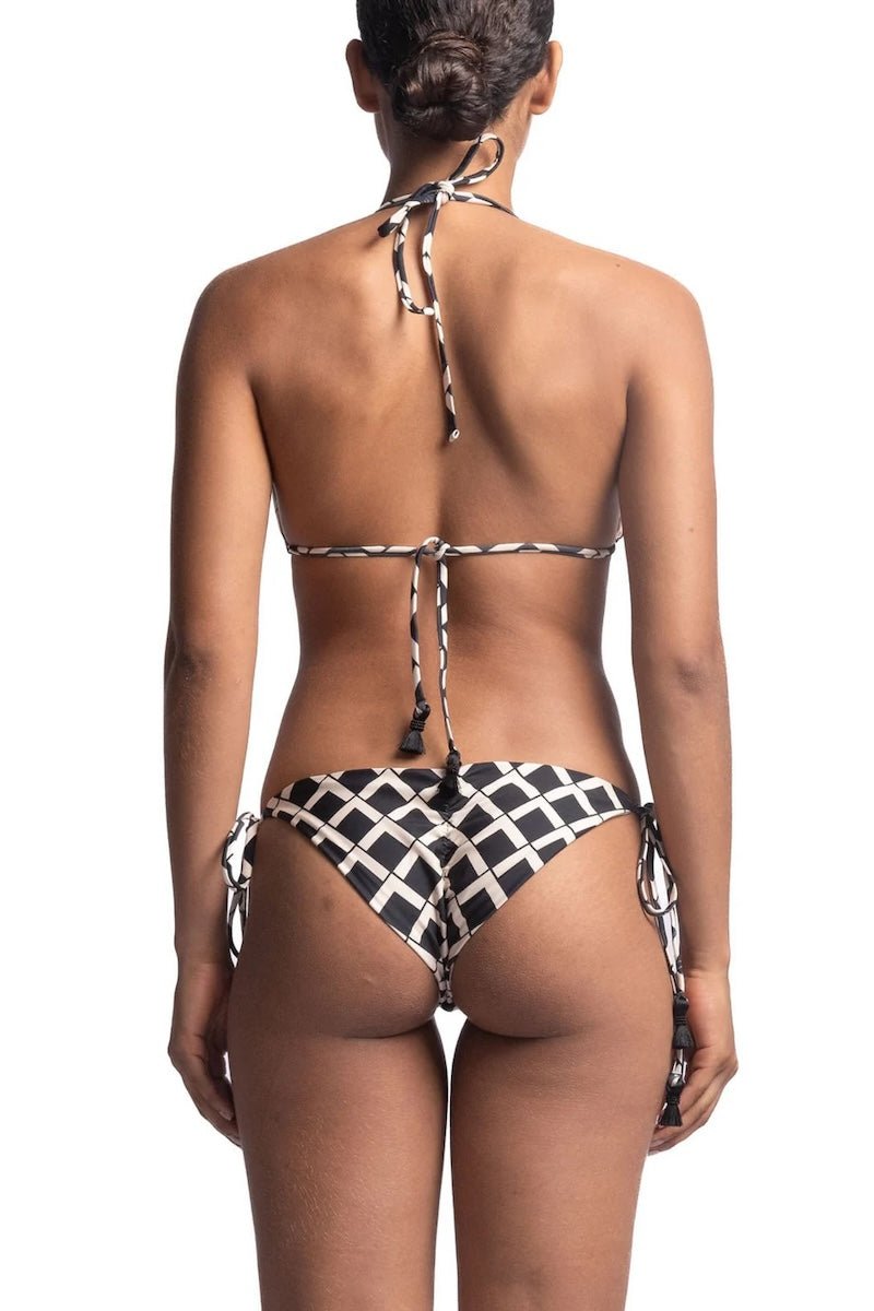 Close up of the back of a woman wearing a black and white bikini set. She's in front of a white background. The purpose of this image is to highlight the bikini, which is available for sale at EVAMAIA Boutique in Studio City, CA.