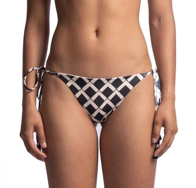 Close up of the back of a woman wearing a black and white bikini bottom. She's in front of a white background. The purpose of this image is to highlight the bikini, which is available for sale at EVAMAIA Boutique in Studio City, CA.