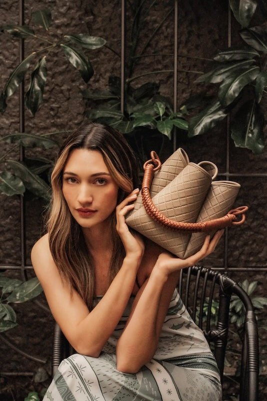 Image of a woman holding the Tulip Baletti leather handbag in grey and camel. The purpose of the image is to highlight the bag because it is for sale at EVAMAIA boutique in Studio City, CA and online.